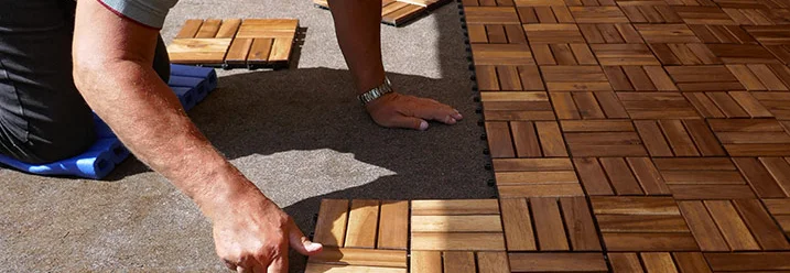 Person verlegt Holzfliesen auf einer Terrasse